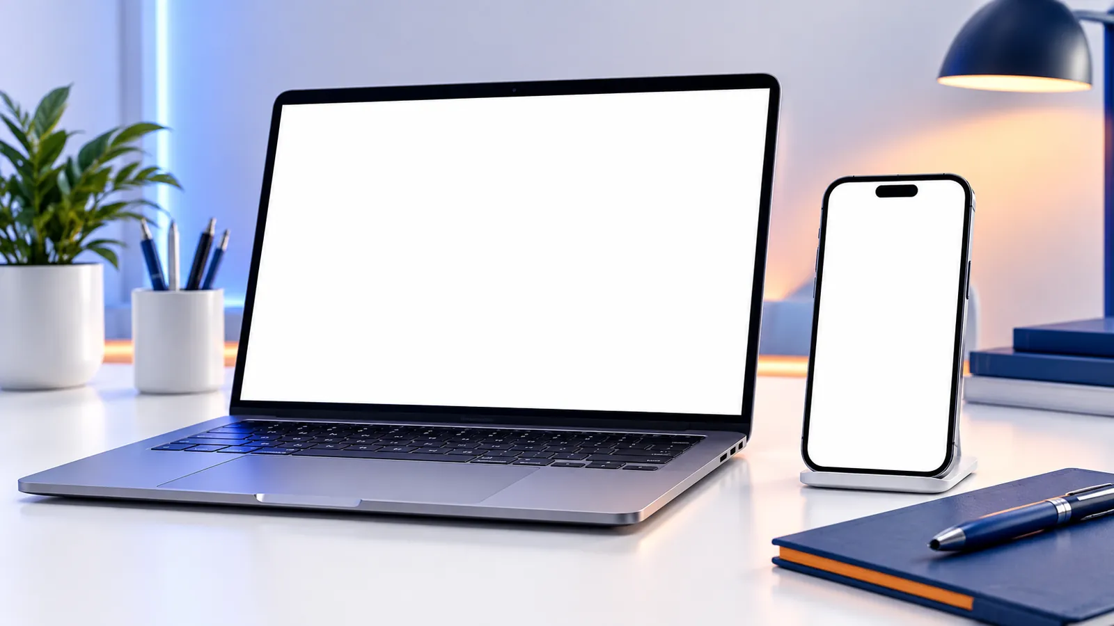 A MacBook laptop and a smartphone on a clean desk, ready to display an app and website interface